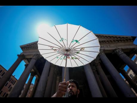 A man shields from the sun with a paper umbrella in front of Rome's Pantheon during a heat wave, Thursday, July 11, 2024. Italian authorities declared a red weather alert in seven cities on Thursday, mostly in the central parts of the country but also the 