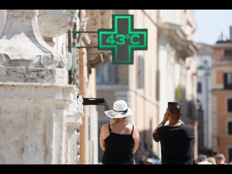 A man takes a photo of the temperature of 43 degrees C (109 degrees F) recorded in the sun outside a pharmacy in downtown Rome, Thursday, July 11, 2024. (Cecilia Fabiano/LaPresse via AP)