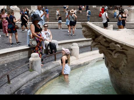 A girl cools off in the Barcaccia fountain near the Spanish Steps in downtown Rome, Thursday, July 11, 2024. (Cecilia Fabiano/LaPresse via AP)