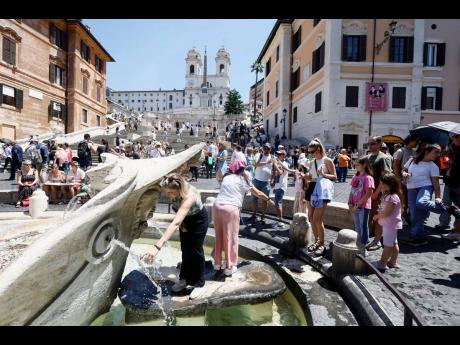 Tourists line up to fill their water bottles and cool off at the Barcaccia fountain beneath the Spanish Steps in downtown Rome yesterday.