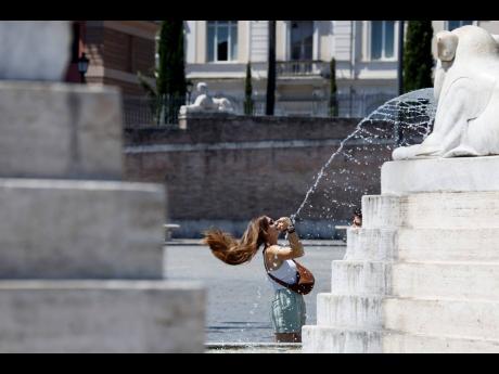 A woman shakes out her hair by a fountain in Piazza del Popolo Square in downtown Rome, Thursday, July 11, 2024. (Cecilia Fabiano/LaPresse via AP)