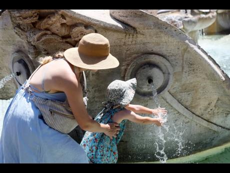 A child cools her hands in the Barcaccia fountain near the Spanish Steps in downtown Rome, Thursday, July 11, 2024. (Cecilia Fabiano/LaPresse via AP)