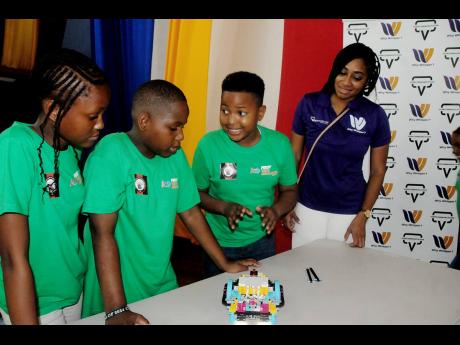 Blair Whittingham (right), sales and marketing lead strategist  at Verb Communication, looks on as St Jude’s Primary students (from left to second right) Shaquasi Watson, Shawn Stewart and Jhonoi Knight discuss the program-coded qualities of their Lego r