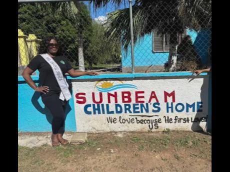 Thompson poses next to the sign at Sunbeam Children’s Home in Old Harbour, Jamaica. In collaboration with the Everyone Has A Story Foundation, she provided gifts to 60 boys residing there.
