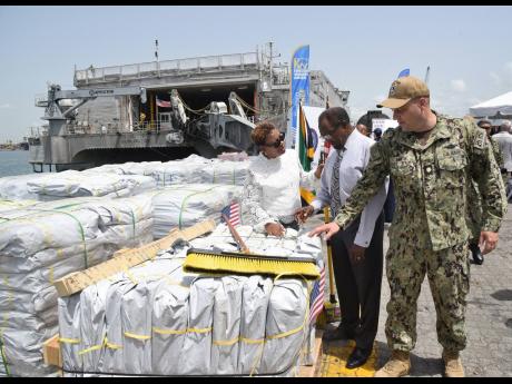 United States Ambassador Nick Perry (centre) looks at relief supplies handed over to Jamaica by the US at the Kingston Wharves on Wednesday. With him are Lieutenant Commander Zachary Smith (right), mission commander, and Dr Nicole Dawkins-Wright, director 