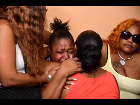 Venasia Stewart (centre), Alric Moncrieffe’s mom, is consoled by relatives after the discovery of her son’s body on Thursday.