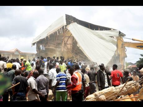 People and rescuers gather at the scene of a collapsed two-storey building in Jos, Nigeria yesterday.