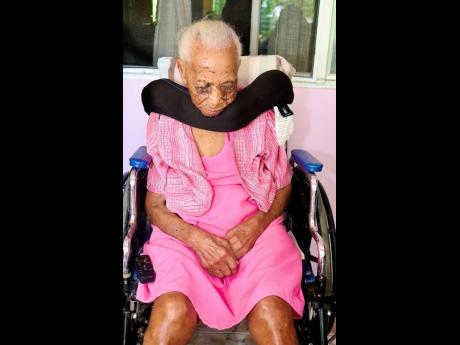 File photo shows Nora Miller-Welsh, super-centenarian, sitting in her wheelchair while waiting in anticipation of a visit from Pearnel Charles Jr., Minister of Labour and Social Security, in observance of Centenarians’ Day.