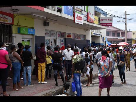 
In this 2020 photo people are seen gathered along the main street in Linstead waiting to access remittances. 