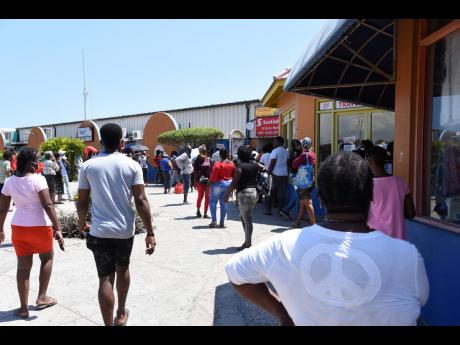 In this April 2020 photo people are seen waiting in Portmore Shopping Mall to collect their remittances. 