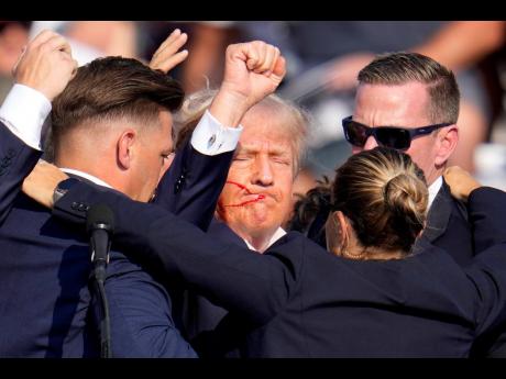 Republican presidential candidate former President Donald Trump is helped off the stage by US Secret Service agents at a campaign event in Butler, Pennsylvania.