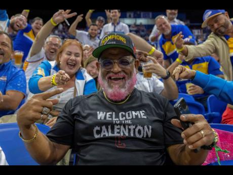 A Gigantes de Carolina fan sits amid Vaqueros de Bayamón fans, during a basketball game between Bayamon and the Guaynabo Mets in Puerto Rico.