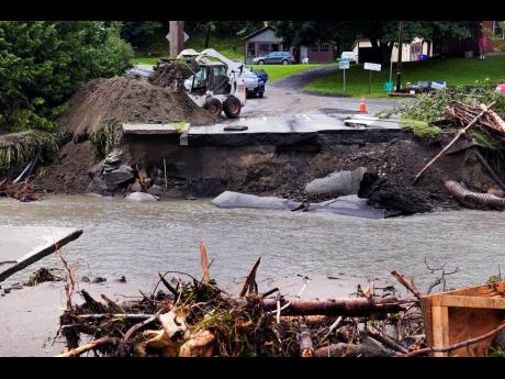 A loader dumps dirt along a washed out portion of Mill Street after remnants of Hurricane Beryl caused flooding and destruction, Friday, July 12, in Plainfield, Vermont. 