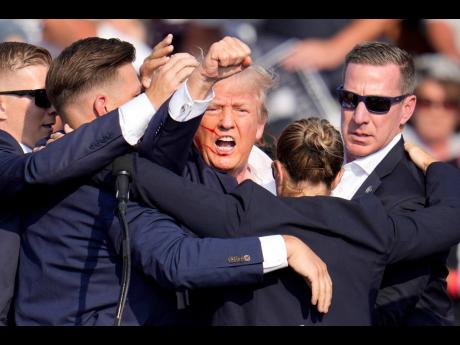 Republican presidential candidate former President Donald Trump is helped off the stage by US Secret Service agents at a campaign event in Butler, Pennsylvania.