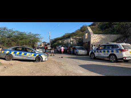 Onlookers, mostly residents from the apartment where Marco-Miche Downer lived, gather at the scene after hearing news of the discovery of his body at the Forum Beach in Portmore, St Catherine, in May.