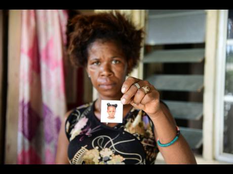 Marie Beckford holds a photo of her missing 10-year-old daughter, Neisha Hinds, at their home in Spanish Town, St Catherine, on Monday.