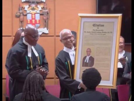 Justice Patrick Brooks, outgoing president of the Court of Appeal, receiving a citation from Chief Justice Bryan Sykes at a special sitting of the Court of Appeal on Wednesday.