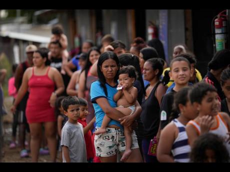 Venezuelan migrant Minorca Parra holds her daughter Karin Alvear as she lines up to receive food in a temporary camp after crossing the Darien Gap from Colombia in Lajas Blancas, Panama, on June 27.