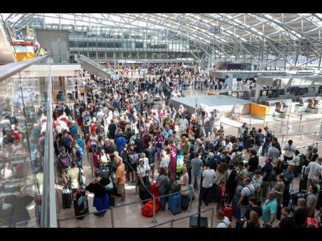 Travellers wait in Terminal 1 for check-in at Hamburg Airport, in Hamburg, Germany yesterday as a widespread Microsoft outage disrupted flights, banks, media outlets and companies around the world.