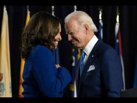 Then Democratic presidential candidate former Vice President Joe Biden and his running mate, then Senator Kamala Harris, pass each other as Harris moves to the podium to speak during a campaign event in Wilmington, Delaware, on August 12, 2020.