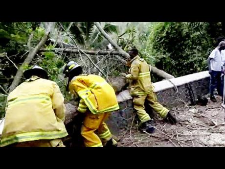 Firefighters clearing sections of the roadblock along the corridor in Junction, St Mary, on Monday.