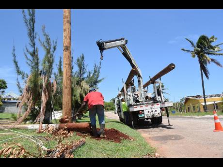 A work crew replacing a broken utility pole along the Southfield to Flagaman main road in St Elizabeth last week.