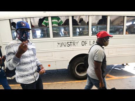 Jamaica farm workers disembark a Ministry of Labour and Social Security bus at the Norman Manley International Airport.