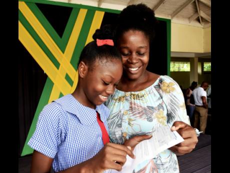 Amelia Brown (left) and her mother Athlene Brown (right), smile as they read the details of the bursary from the Poverty Alleviation and Empowerment Foundation.  The family was presented during a ceremony for scholarship recipients at the Spanish Town SDC 