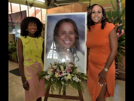 Dr Tarika Barrett (left) and Monifa Barrett (right), daughters of Betty Ann Blaine, stand beside a portrait of the late child rights advocate at the service of thanksgiving for Blaine’s life at the Boulevard Baptist Church in St Andrew on Thursday.