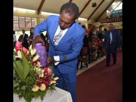 Craig Foster from Sam Isaacs and Son Funeral Home places the urn with the remains of Betty Ann Blaine on a table ahead of her funeral service at the Boulevard Baptist Church in St Andrew on Thursday.