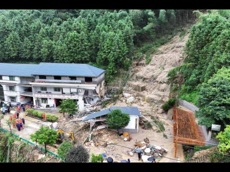 In this drone photo released by Xinhua News Agency, a landslide destroys a house in Yuelin village of Shouyue town of Hengyang city, central China’s Hunan Province.