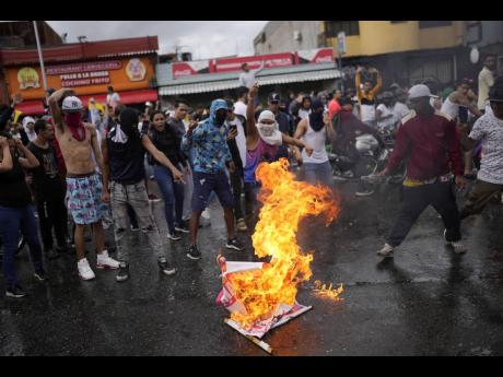 Protesters burn an election campaign poster of President Nicolas Maduro as they demonstrate against the official election results declaring him the winner on Monday, July 29. the day after the presidential election in Caracas, Venezuela, 