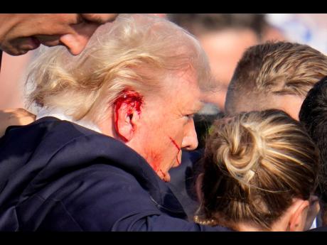 Republican presidential candidate former President Donald Trump is escorted to a motorcade following an attempted assassination at a campaign event in Butler, Pennsylvania, on Saturday, July 13.