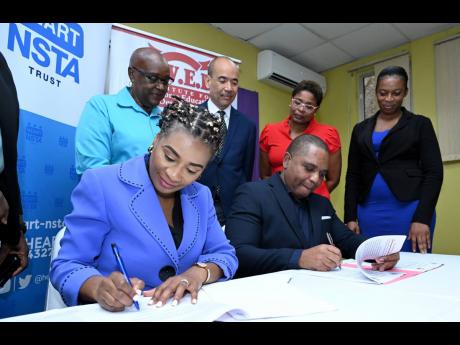 Don Gittens (right), chief executive officer of the Institute for Workforce Education (IWED), and Dr Taneisha Ingleton (left), managing director, HEART/NSTA Trust, sign a memorandum of understanding between the two entities while looking on from left are A