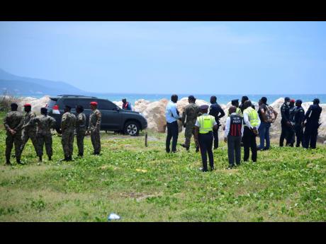 Investigators from the Jamaica Constabulary Force process the scene along the Palisadoes strip where 30-year-old armyman Sekou Medder was found dead in a service vehicle on Monday morning.