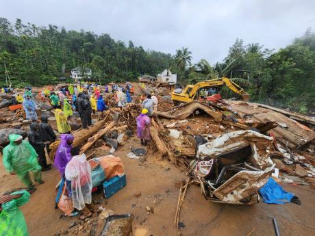 Rescuers and others stand amid debris after landslides hit hilly villages in Wayanad district, Kerala state, India, on Tuesday.