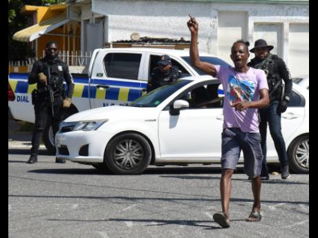 A Vybz Kartel fan is watched by the police while celebrating his release in Gaza City, Waterford, Portmore, in St Catherine shortly after the verdict was handed down by the Court of Appeal yesterday.