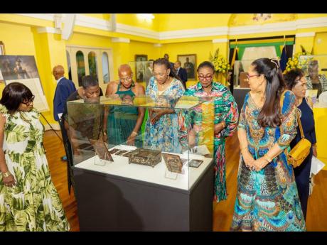 Visitors on the Taino exhibition tour last week at King’s House view the artefacts on display. 