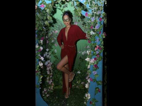 Anya Davis rocks a high-split burgundy dress, striking a playful pose for the camera.