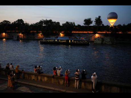 
People take photos of the Olympic cauldron at sunset in the Tuileries Gardens during the 2024 Summer Olympics.