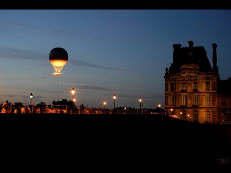 The Olympic cauldron beams at sunset in the Tuileries Gardens during the 2024 Summer Olympics.