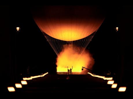 Teddy Riner and Marie-Jose Perec watch as the cauldron rises in a balloon in Paris.