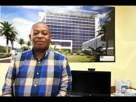 UHWI CEO Fitzgerald Mitchell stands in front of an architectural rendering of the to-be-constructed first tower under the expansion project at the St Andrew-based hospital.