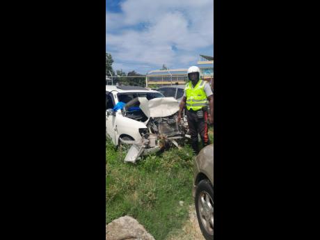 Sergeant Courtney Miller, head of traffic in the St Ann Police Division, examining a vehicle that was involved in a crash.