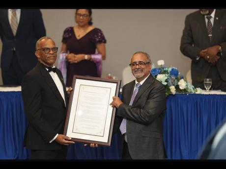 Dr Delroy Fray (right) presents a citation to Dr Derek Harvey.