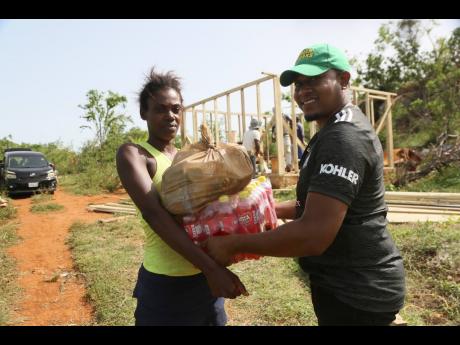  Roseann Crowe, a mother of five who lost her house in Hurricane Beryl, receives a donation of Busta Soft Drinks on July 27 from Floyd Green, member of parliament.