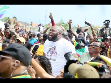 Mikhail Green of Mitchell Town celebrates his cousin Kishane Thompson’s silver medal run in the 100m during a watch party at the community field in Clarendon yesterday.