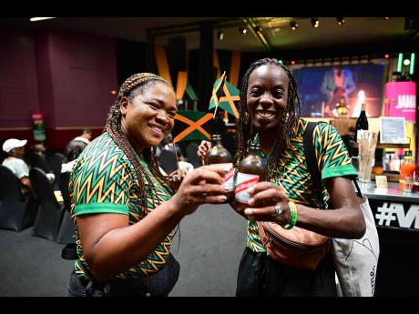 Kasha Spence (left) and Sadria Warner enjoy a cold Red Stripe beer  during their visit to Jamaica House in Paris yesterday. Jamaica House is situated less than 700m away from the Stade de France. 