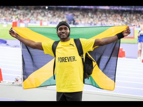 Wayne Pinnock parades the Jamaican flag in celebration of his silver medal in the men’s long jump on Tuesday.