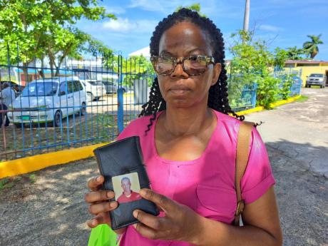 Mercia Fraser, the mother of Mario Deane, holds up a small picture of her son while recounting her frustration at the lack of closure 10 years after his death on August 6, 2014. He died three days after he was beaten while in custody at the Barnett Street 